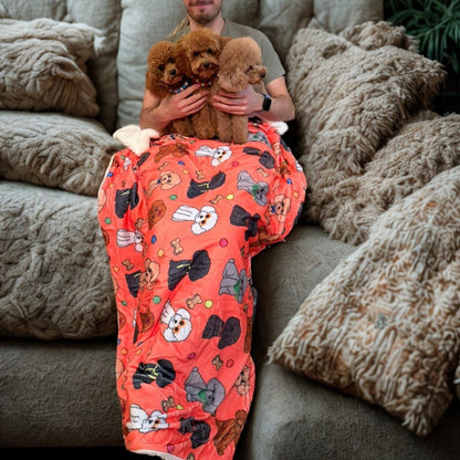 Manta suave coral con dibujos de caniches de la colección Caniche con tres caniches tumbadas encima.